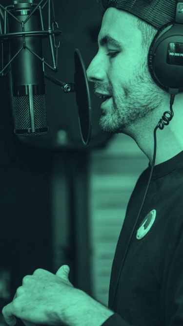 man wearing cap and headsets, talking in front of a mic